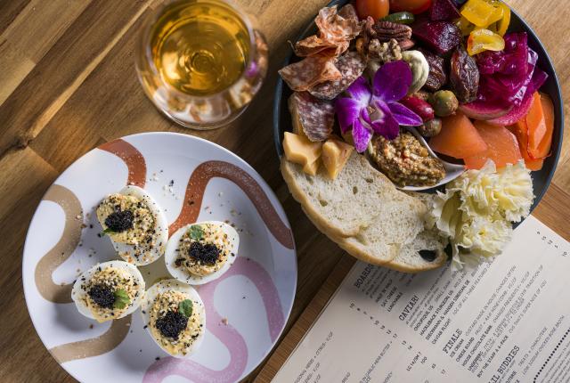 Deviled eggs topped with black caviar and herbs on a small serving plate.