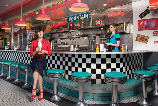 A woman sits at 66 Diner with a milkshake.