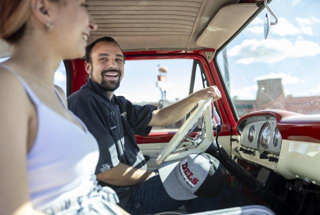 Chase waters smiling in the driver's seat of a red classic truck.