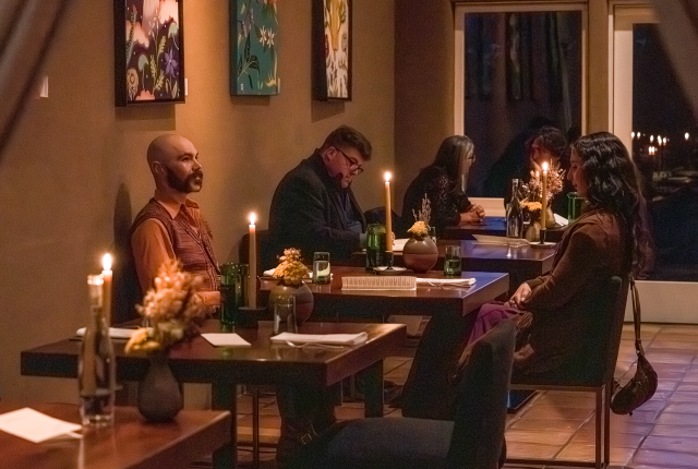A softly lit dining room with stucco walls, modern chairs, and a fireplace creating a cozy atmosphere.