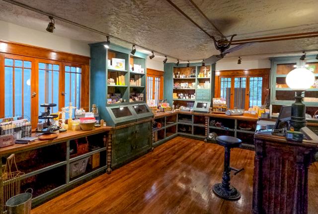 Cozy vintage-style shop interior with wood floors, teal shelves, and various items displayed.