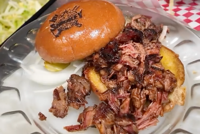 Pulled pork sandwich on a toasted bun, served with golden barbecue crust and sauce.