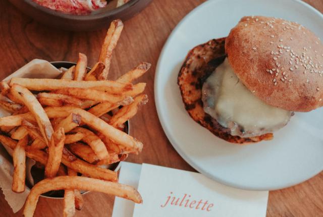 A plated cheeseburger with hand-cut fries presented on a stylish restaurant table.