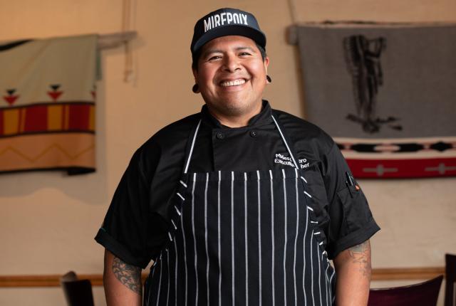 Chef Myles Lucero standing in the Prairie Star kitchen, wearing his chef coat.