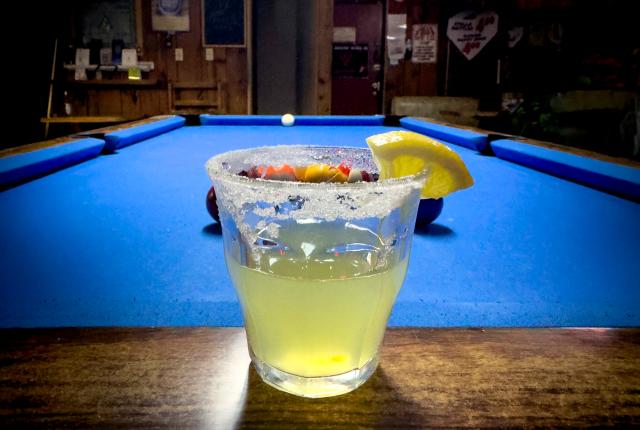 Salt-rimmed cocktail with a lemon wedge beside a pool table at Raymond's Lounge in Truth or Consequences.