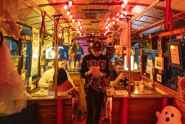 Guests inside the Ghost Light Saloon's renovated trolley, with string lights and license plates covering the ceiling.