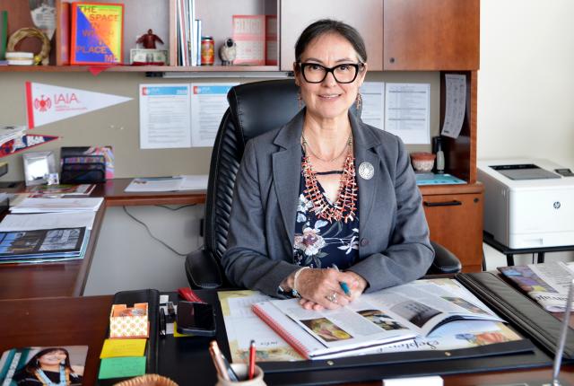 Shelly C. Lowe, president of the Institute of American Indian Arts, sits at her desk in her Santa Fe office surrounded by books and papers.