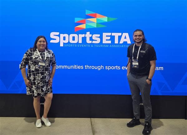 Angela and Ryan pose in front of the Sports ETA at the 2025 event.