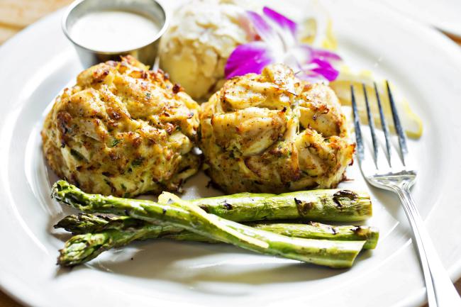 Two large lump crab cakes and asparagus on dinner plate