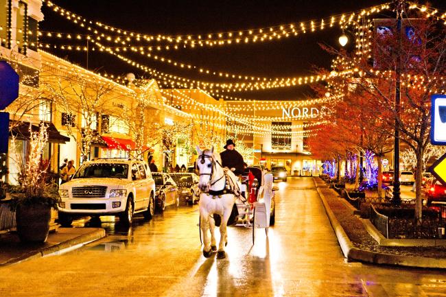 Horse-drawn carriage riding under strung twinkle lights during holiday season at Easton Town Center