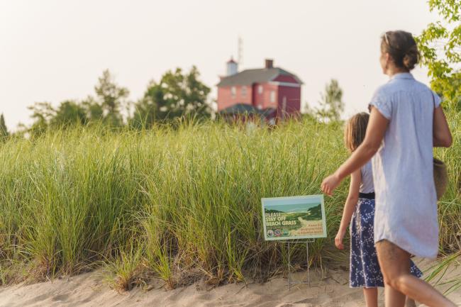 A sign that says "please stay off the beach grass"