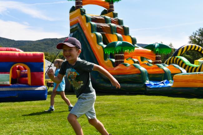 Waterville Valley Recreation Department - Chalk Fest (Kid Running Past Inflatable Slide with a Smile)