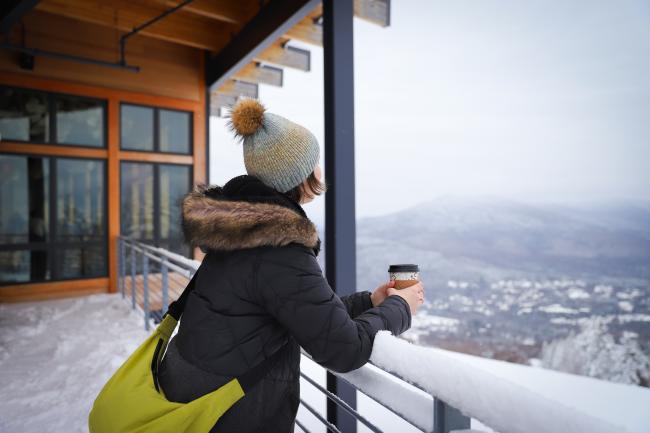 Woman Looking Out at Snowy View Holding Coffee