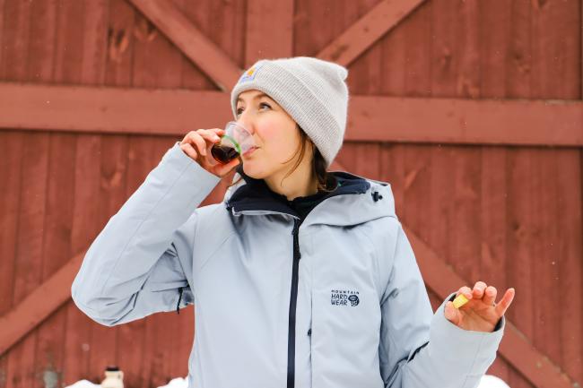 Girl Sipping Maple Syrup in Winter Clothes (Red Barn in Background)