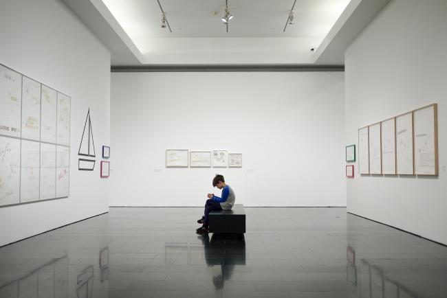 Boy-sitting-on-a-museum-bench-looking-at-his-phone