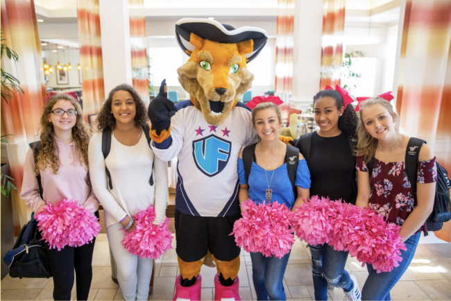 A fox mascot stands with a group of young women