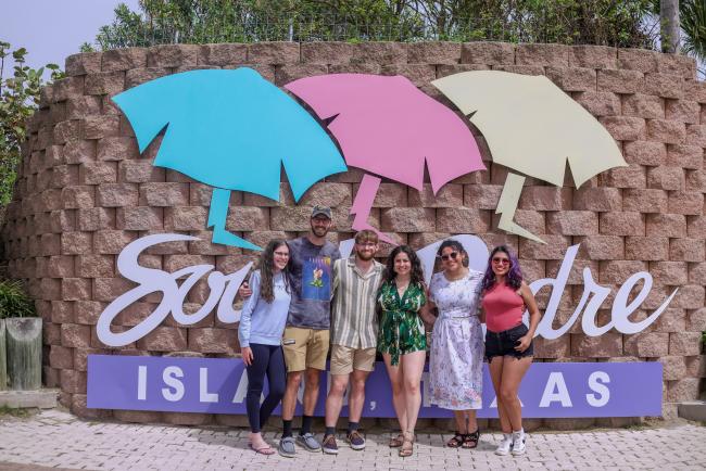family taking photo in front of the South Padre Island welcome sign