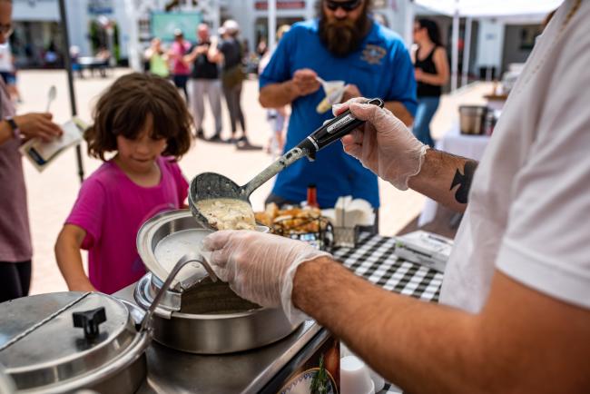 man serving a bowl of chowder to a young girl at a chowder festival