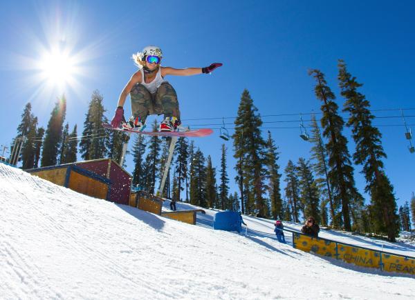 Sun beams in the sky, as snowboarder soars through the air