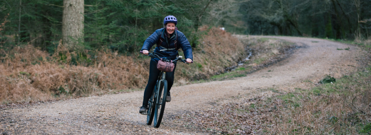 Woman cycling downhill on gravel track in the New Forest
