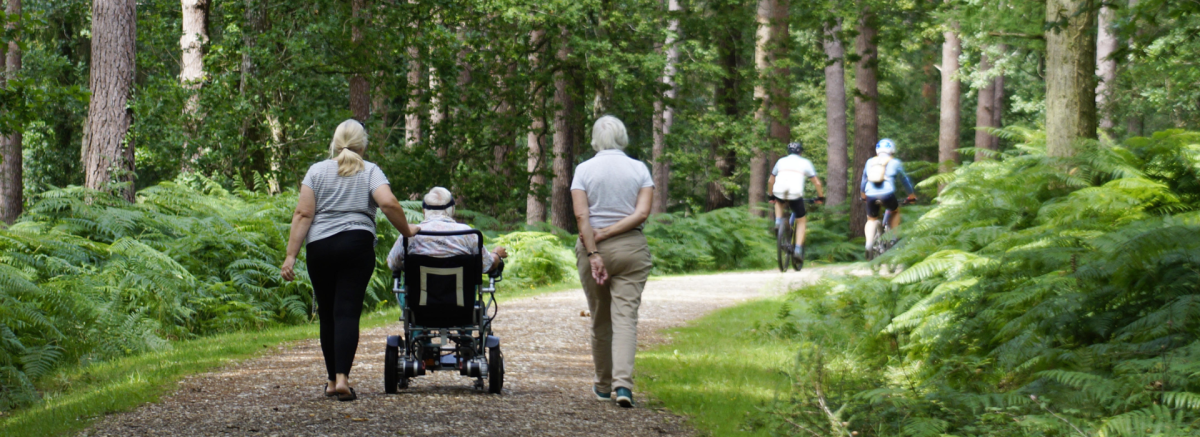 Two people walking with mobility scooter along walking path in the New Forest