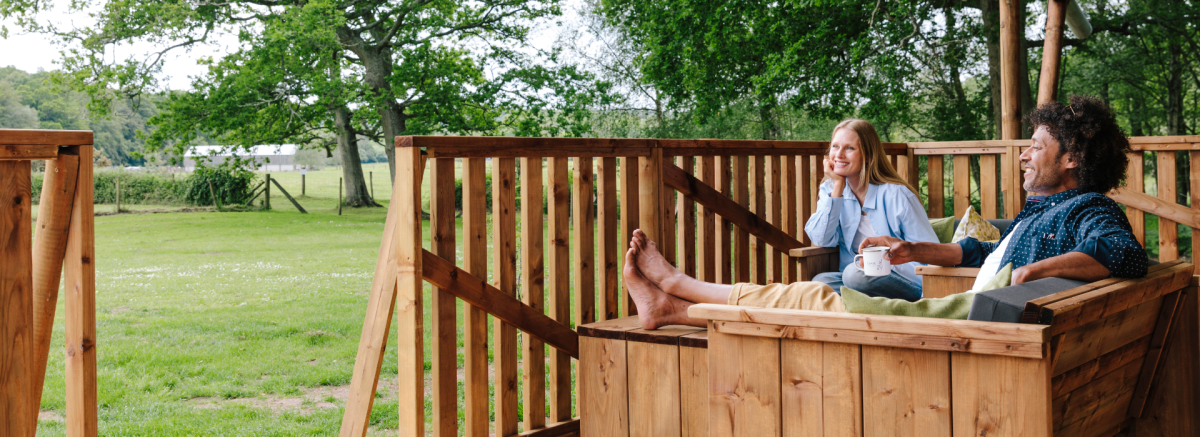Two people on balcony of glamping safari hut at Green Hill in the New Forest