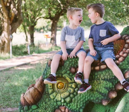 Two boys, roaring while sitting on top of a dinosaur at The Heard