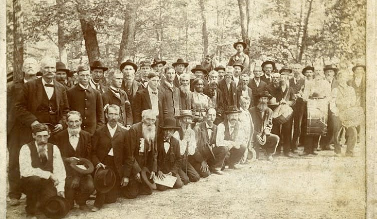Black and white photo of several men surrounding Lucy Higgs Nichols