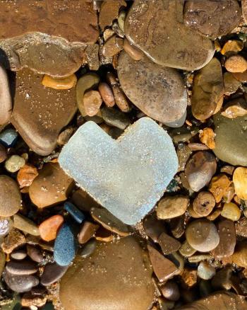 Heart beach glass in rocks by Charlotte Hernandez