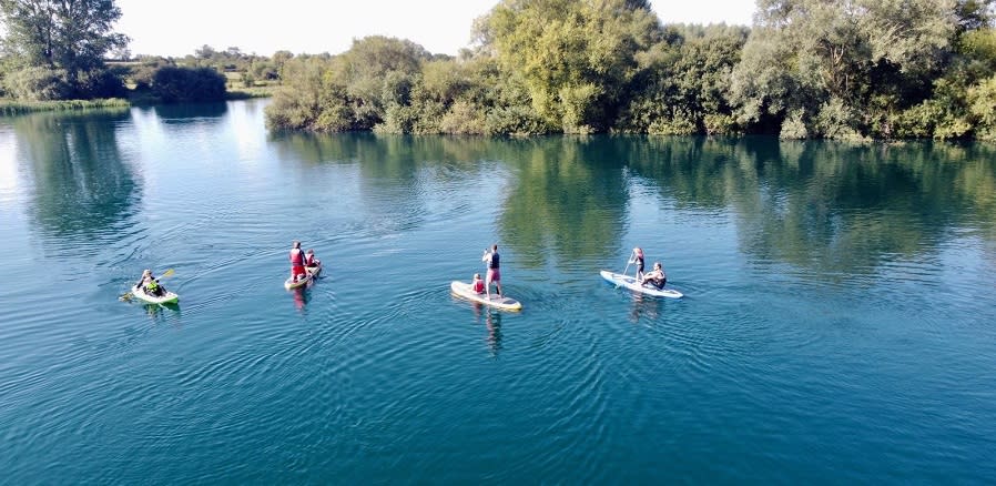 A group of people paddle boarding and kayaking on a lake