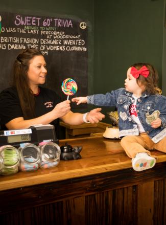 Little girl reaches for lollipop at Peppermint Stick Candy Store