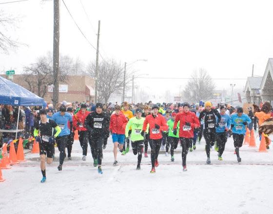 A large group of runners heads down the street in a light snow during the Turkey Stampede in Elkhart County, IN