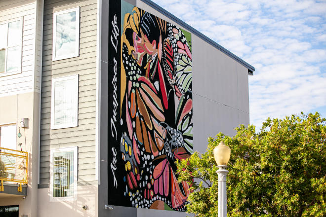 Mural painting shows man kissing woman dressed in colorful attire