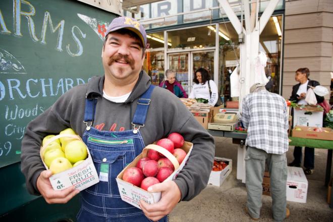 Smiling producer holding apples at Roanoke City Farmers Market 