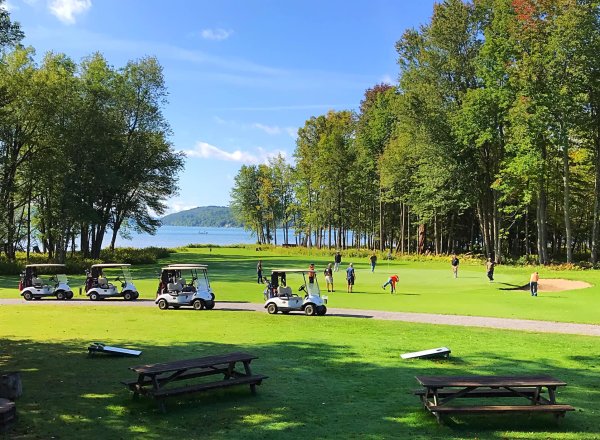 Golfers playing Otsego Golf Club with Otsego Lake in the background