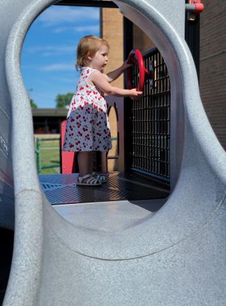 little girl playing at steering wheel on playground