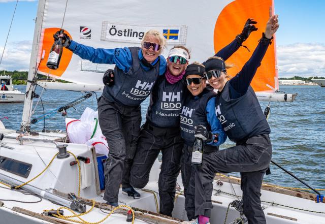 three women wearing sailing gear posing for a celebratory photo on a sailboat for Santa Maria Cup