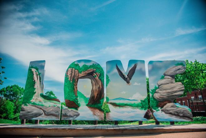 Large painted letters spell the word "LOVE" in front of a blue sky