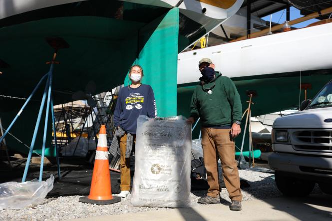 The Woodwind crew holds up the bag of recycling from the boat unwrapping.