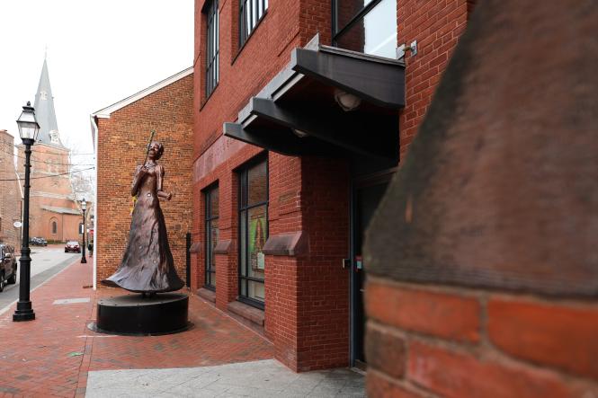 A brown building with a large bronze statue in front of it.