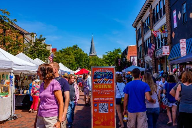 people walk down West Street at the First Sunday Arts Festival