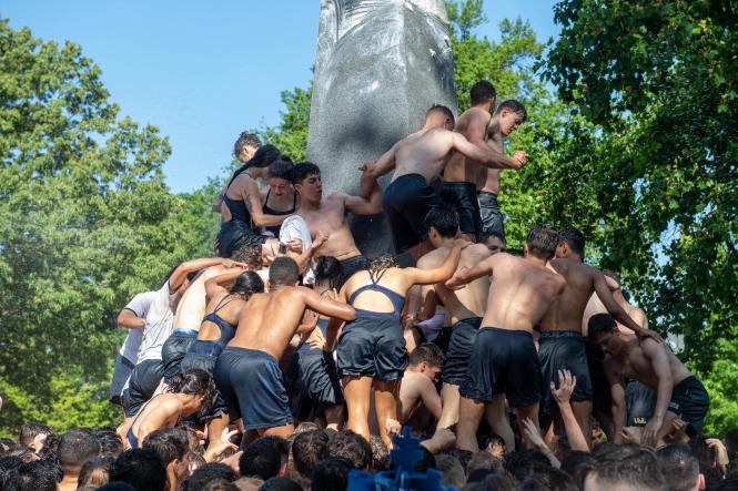 men and women enrolled at the Naval Academy climb the Herndon Monument