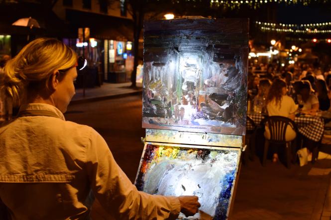 a woman paints a city scene at night