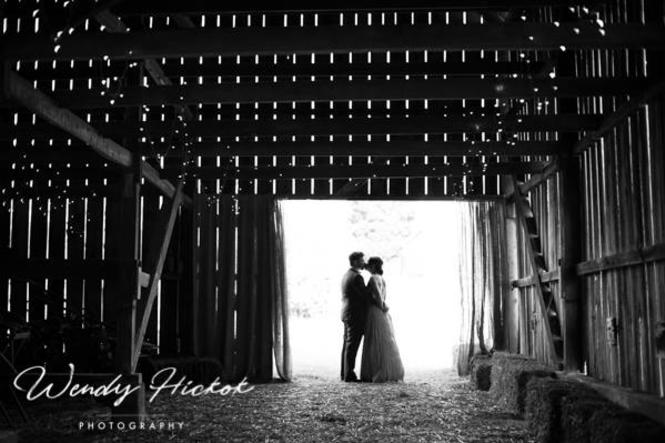 A wedding couple kisses in the barn at Harwood Hills Farm.