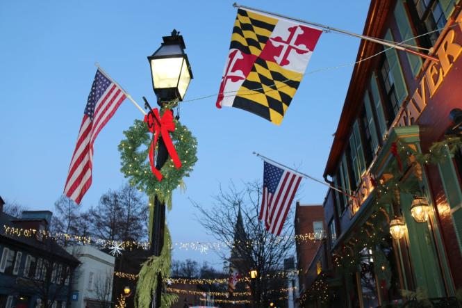 American flags and Maryland flags with greens and garland on a light post on West Street