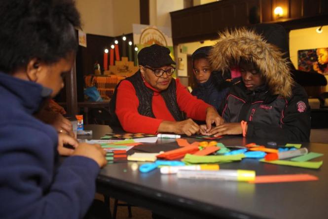 A black family works on a Kwanzaa craft at a table