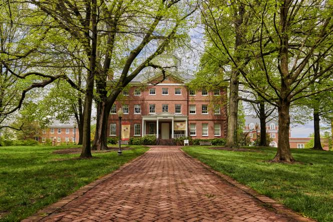 A brick fronted historic building on a brick lined walkway flanked by trees