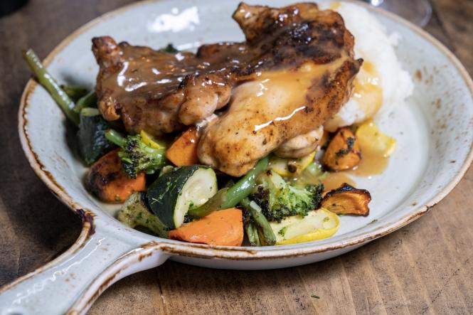 A plate of chicken and gravy over vegetables