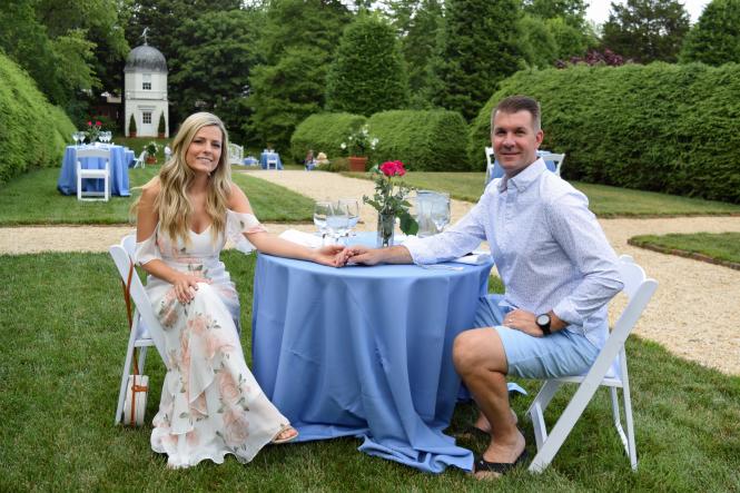 A couple holds hands at their table in Wine and Dine in the Garden