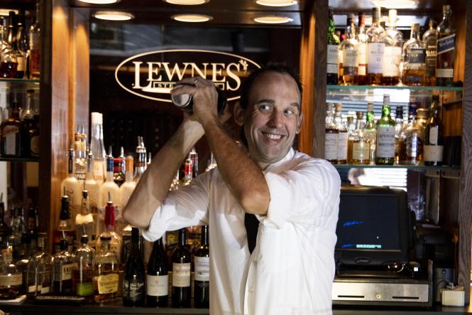 Man shakes a martini shaker behind the bar at Lewnes Steak House